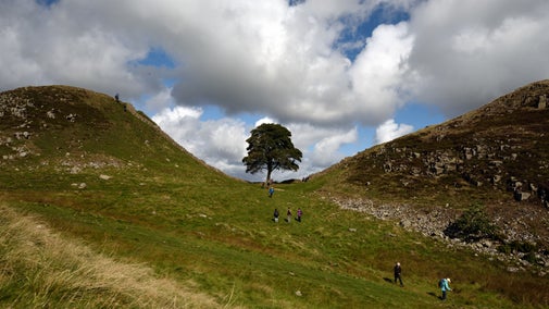 Walkers on the path besides the wall at Hadrian's Wall and Housesteads Fort, Northumberland